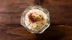 Crema al mascarpone decorata con cacao in una coppetta di vetro su sfondo in legno