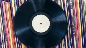Un disco in vinile nero su una collezione di copertine colorate di altri dischi