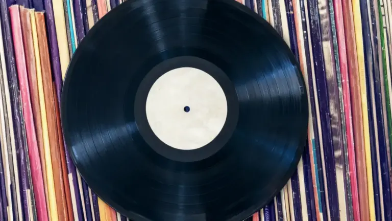 Un disco in vinile nero su una collezione di copertine colorate di altri dischi