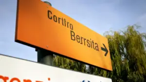 Cartello stradale arancione in una zona urbana con alberi sullo sfondo