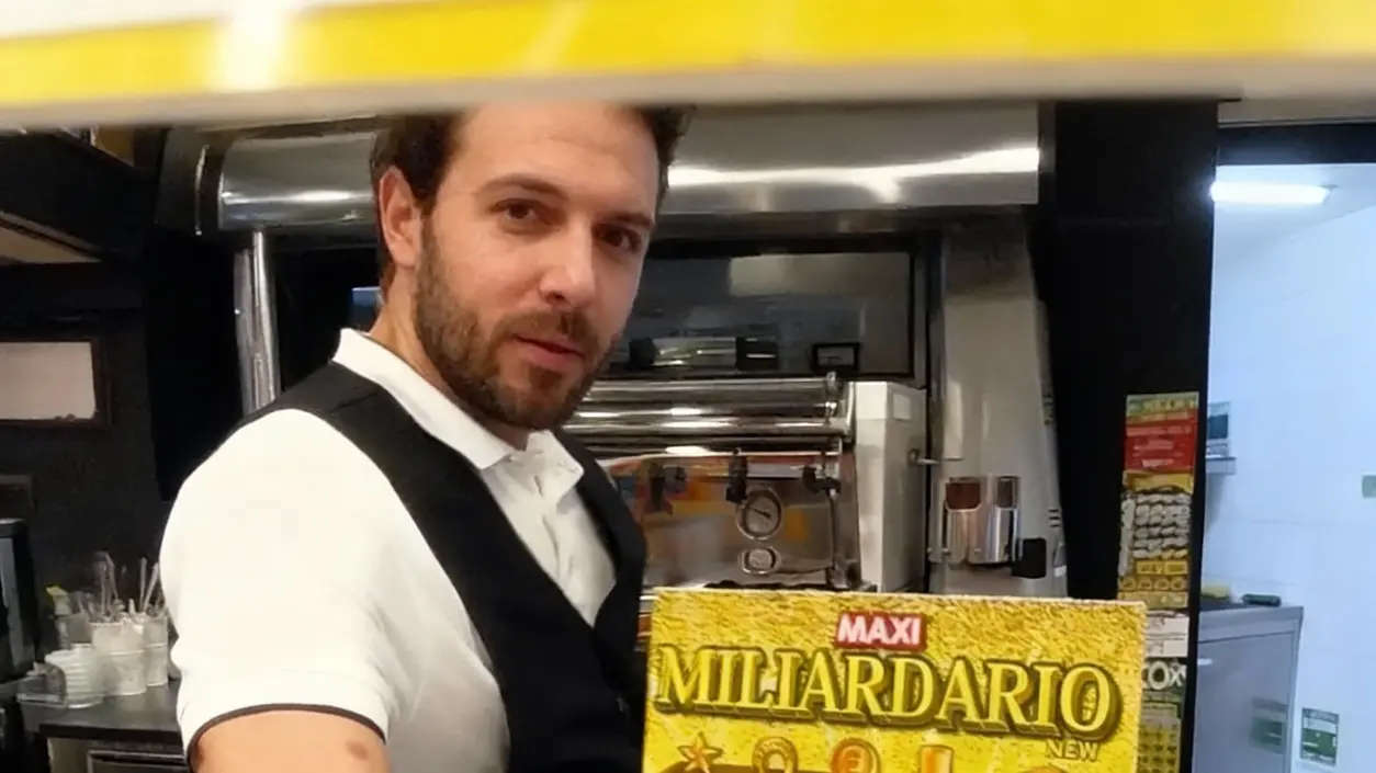 Una persona mostra un biglietto gratta e vinci all'interno di un bar