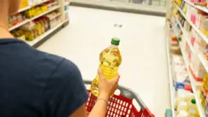 Persona con bottiglia di olio in un supermercato