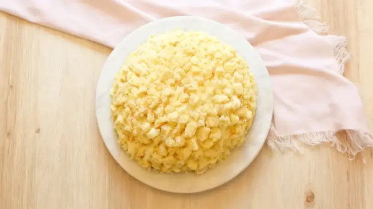 Torta mimosa soffice su piatto bianco, vista dall'alto su tavolo di legno chiaro