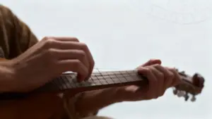 Mani che suonano uno strumento a corda su sfondo chiaro