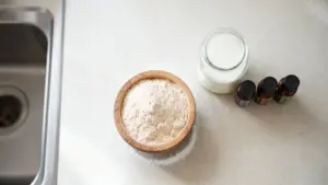 Ciotola di polvere naturale accanto a un barattolo di vetro e flaconcini su un piano cucina